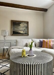 Hochwertige Innenraumgestaltung im Wohnzimmer mit Wandpaneelen, sichtbarem Holzbalken und hellem Wandanstrich – Wohnraumgestaltung Wien.