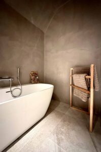 Moderne und edle Wandbeschichtung in einem Badezimmer. Links steht eine weiße Badewanne und rechts liegen Handtücher